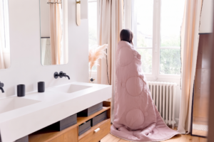 Femme enveloppée dans la couette Sénane Loulenn vieux rose, collection Trinité
