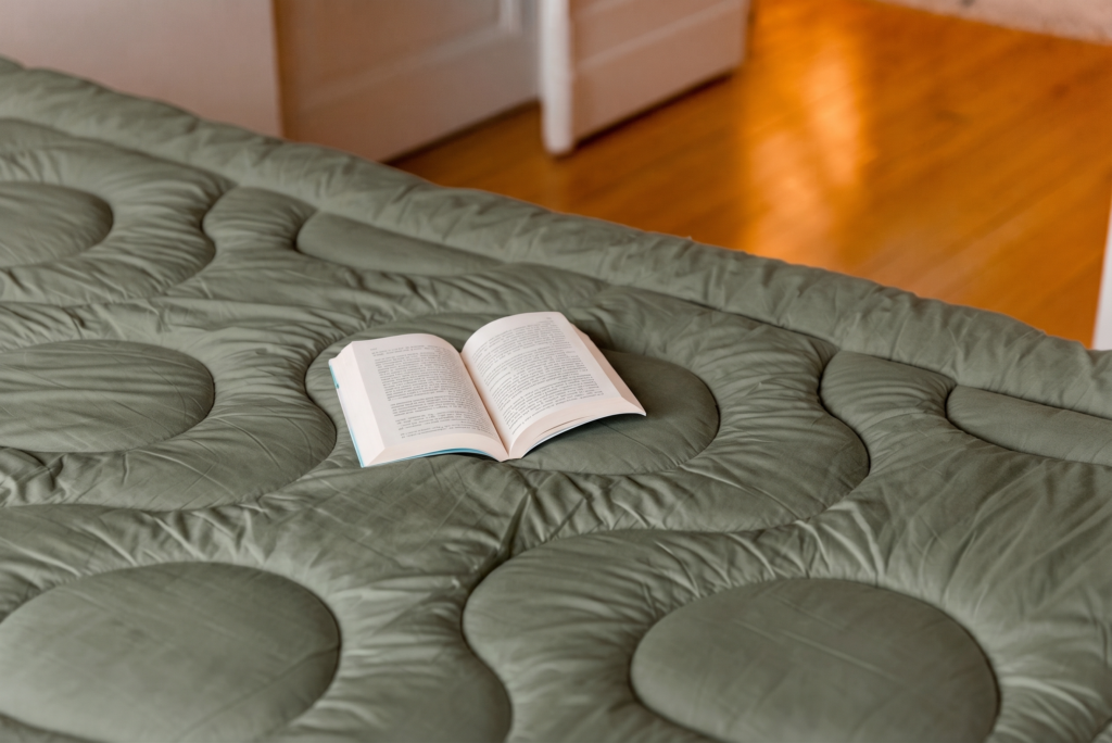 Surmatelas Bréhat Loulenn de la collection Trinité, coloris vert olive, avec un livre ouvert