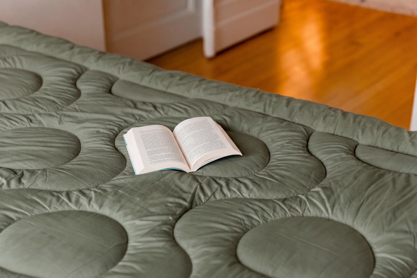 Surmatelas Bréhat Loulenn de la collection Trinité, coloris vert olive, avec un livre ouvert
